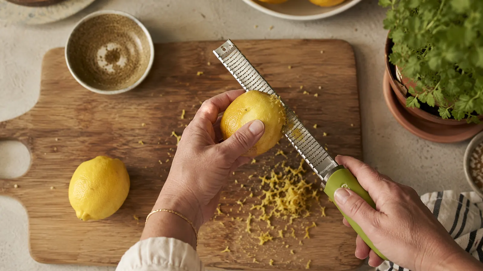 Microplane zester shaving bright yellow lemon zest onto a wooden cutting board
