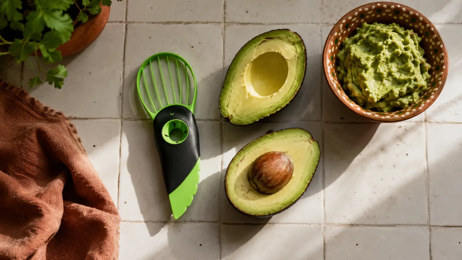 NADOBA 3-in-1 avocado tool resting on a wood cutting board next to two halved avocados