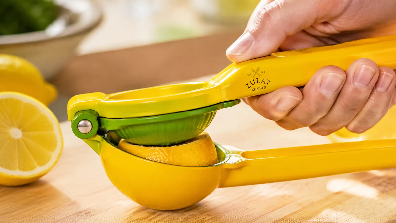 Close-up of a halved lemon seated inside the perforated bowl of the metal squeezer just before the handles are pressed shut