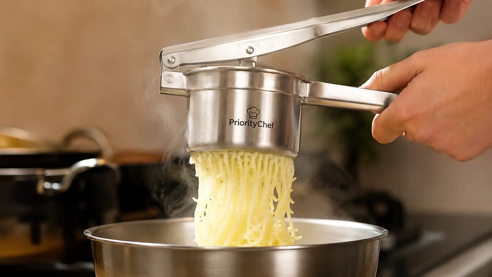 Hand squeezing the potato ricer handles together over a mixing bowl, riced potato falling in fine strands